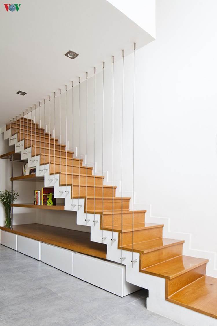 Cầu thang lên tầng thiết kế kiểu gấp khúc tạo ấn tượng. Thay vì lan can là một hệ dây cáp làm nhẹ và thoáng. Gầm cầu thang được tận dụng làm tủ và kệ để đồ.