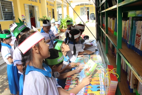  Các em học sinh ở Trường Tiểu học Phú Quới A háo hức đọc sách khi ô tô thư viện lưu động về trường vào tháng 11/2019.