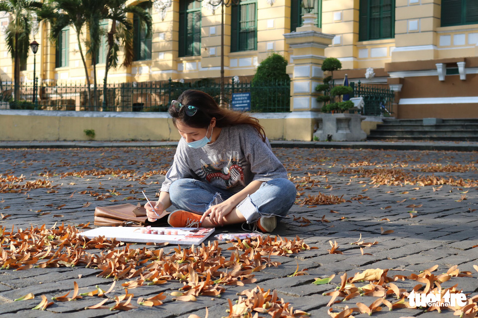 Ngọc Yến (22 tuổi, ngụ Q.5, TP.HCM) tranh thủ hoàn thiện bức tranh màu nước trước bưu điện TP.HCM khi đợi chị gái đọc kinh cầu nguyện ở nhà thờ Đức Bà - Ảnh: HOÀNG AN