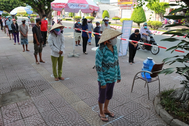 Tại các địa điểm phát gạo, người dân đến xếp hàng trật tự, cách nhau theo quy định khi chờ nhận gạo.