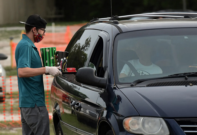 Nhiều xe ô tô xếp hàng tại rạp chiếu phim ngoài trời ở Florida, Mỹ. Xe ô tô khi đến đây phải giữ khoảng cách 3,5 m với phương tiện khác. Đồ ăn được chuyến đến từng xe bởi người phục vụ có khẩu trang và găng tay. Ảnh: Shutterstock.