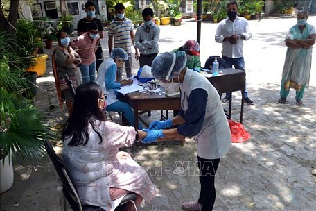 Nhân viên y tế lấy máu xét nghiệm COVID-19 cho người dân tại New Delhi, Ấn Độ. Ảnh: THX/TTXVN