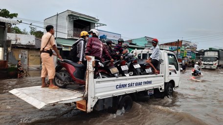 Cảnh sát giao thông cũng xắn quần giúp người dân đưa xe máy lên xe chuyên dụng chở qua chỗ ngập.