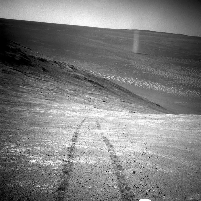 Từ vị trí cao trên một đỉnh núi, năm 2016, xe tự hành Opportunity đã ghi lại hình ảnh một xoáy bụi đang xoắn qua thung lũng bên dưới. Bức ảnh còn in hình bánh của xe tự hành lúc lên dốc. Ảnh: NASA.