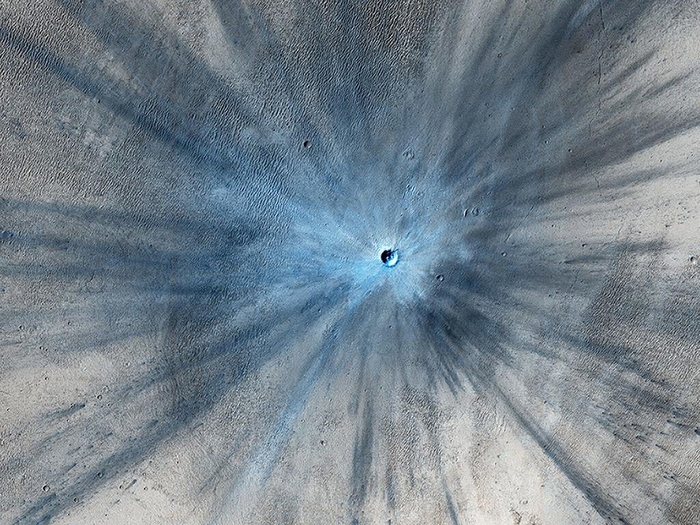 Một miệng núi lửa sau vụ va chạm mạnh được máy ảnh HiRISE chụp vào tháng 11-2013. Miệng núi lửa rộng khoảng 30 mét và được bao quanh bởi một vùng tia rộng lớn do vụ nổ tạo ra. Ảnh: NASA.