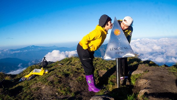 Du khách “tự sướng” với chóp inox ghi độ cao 2.913m của đỉnh núi - Ảnh: Ng.Hường