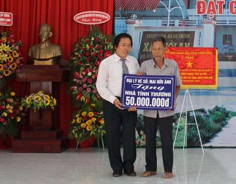 Đại lý vé số Mai Hữu Ánh (trái) tặng 10 phần quà cho học sinh nghèo và trao biểu trưng 50 triệu đồng hỗ trợ xây nhà cho hộ nghèo.