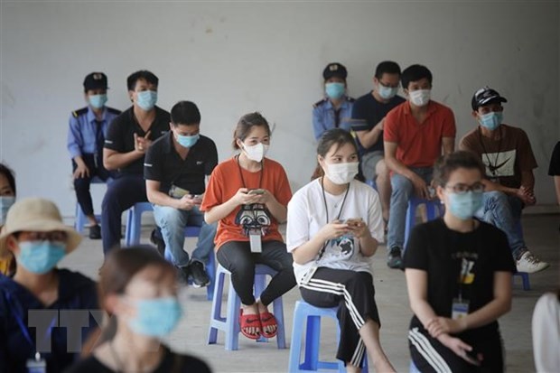 Công nhân Bắc Giang ngồi giãn cách chờ tiêm vaccine. (Ảnh: Danh Lam/TTXVN)