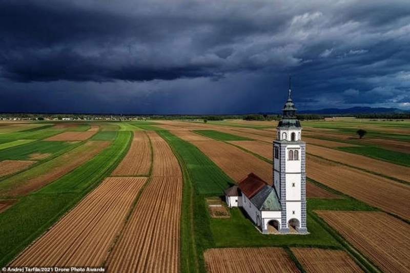 Bức ảnh ấn tượng thuộc hạng mục Đô thị của nhiếp ảnh gia Andrej Tarfila cho thấy nhà thờ Saint Ursula nằm giữa cánh đồng ở thành phố Kranj, Slovenia khi một cơn bão mùa xuân chuẩn bị đến.