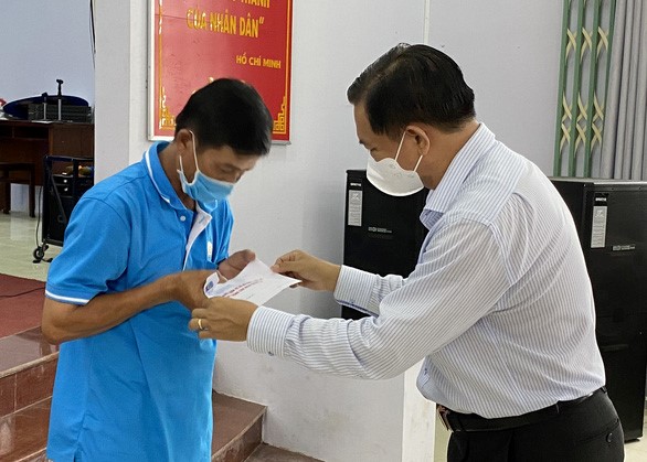 Ông Trần Văn Lâu - chủ tịch UBND tỉnh Sóc Trăng (phải) - trao tiền hỗ trợ cho người bán vé số dạo ảnh hưởng dịch bệnh năm 2021 - Ảnh: K.T.