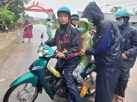 Ông Nguyễn Thanh Vũ  - Chủ tịch UBND xã Bình Đông (huyện Bình Sơn) - dùng xe máy đưa người già yếu đến điểm trú bão (Ảnh: Đình Hiền).