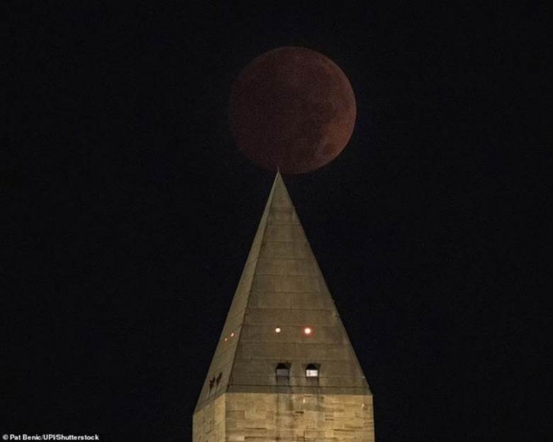 Hình ảnh mặt trăng xuất hiện khá tối và có màu đỏ nhạt bên cạnh Đài tưởng niệm Washington. Ảnh: UPI