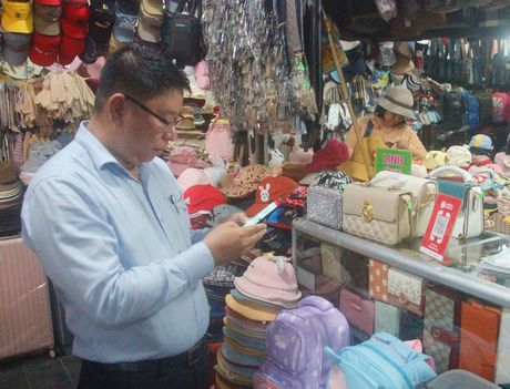 Hoạt động mua bán và thanh toán không dùng tiền mặt ngày càng được ưa chuộng ở chợ Vĩnh Long (ảnh: Người tiêu dùng đang quét mã QR để thanh toán).