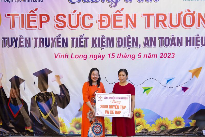 Bà Phạm Thị Lệ- Phó Giám đốc Công ty Điện lực Vĩnh Long (trái) trao bảng biểu trưng tập và xe đạp cho bà Phan Hoàng Tú Nga- Hiệu trưởng Trường THPT Lưu Văn Liệt.