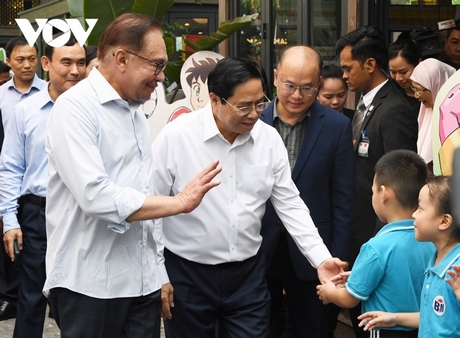 Hai Thủ tướng thăm hỏi các em thiếu nhi trước gian hàng của Nhà xuất bản Kim Đồng. 