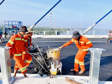 Trên cầu Mỹ Thuận 2, đơn vị thi công khẩn trương hoàn thiện mặt đường nhịp cầu chính, sơn kẻ vạch đường…