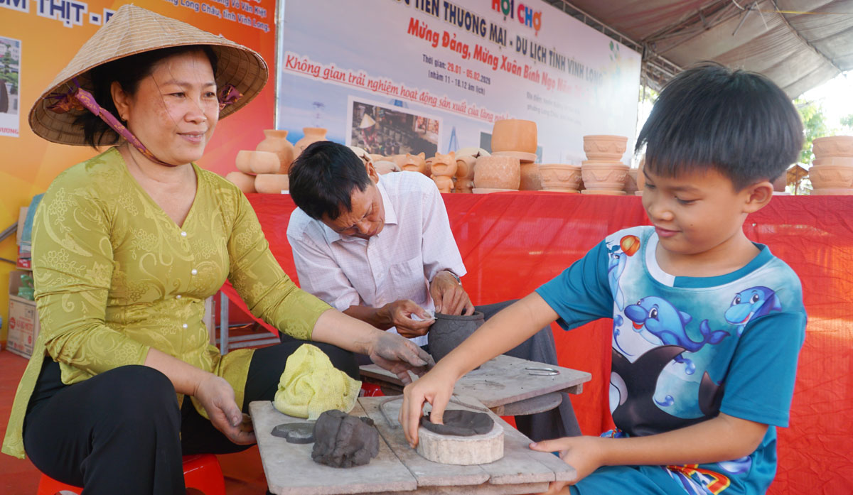 Cô Lâm Thị Huệ (phường Thanh Đức) - thợ làm gốm với kinh nghiệm hơn 20 năm tỉ mỉ hướng dẫn em Trần Hoàng Anh (7 tuổi) tạo hình sản phẩm gốm thủ công.