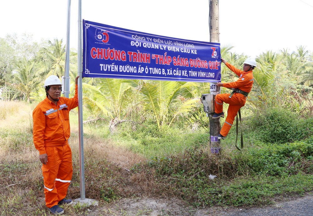 Công nhân Đội Quản lý điện Cầu Kè thực hiện gắn biển công trình.