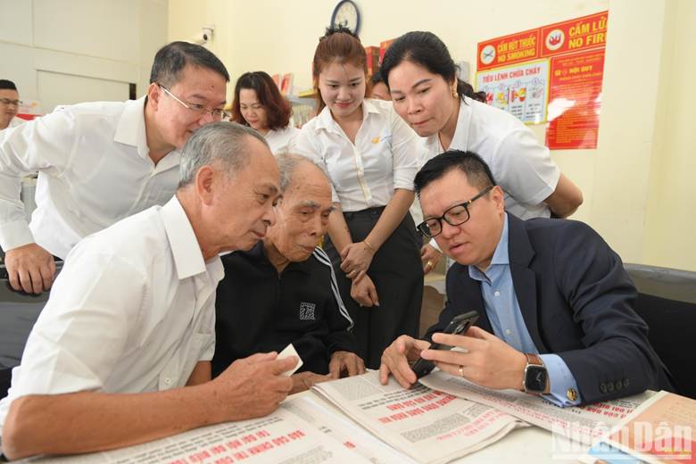 Đồng chí Lê Quốc Minh, Ủy viên Trung ương Đảng, Tổng Biên tập Báo Nhân Dân, Phó Trưởng Ban Tuyên giáo và Dân vận Trung ương, Chủ tịch Hội Nhà báo Việt Nam, hướng dẫn người dân quét mã QR code trên phụ trương công bố dự thảo các văn kiện trình Đại hội XIV của Đảng.