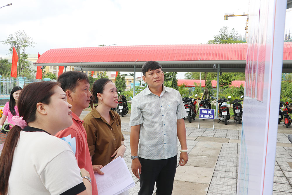 Lãnh đạo phường Long Châu kiểm tra việc niêm yết danh sách và tiểu sử tóm tắt người ứng cử tại UBND phường.