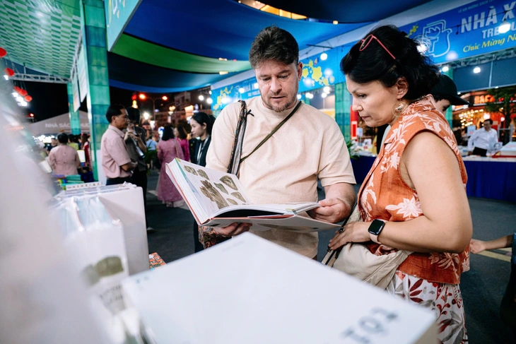 Anh Alessandro (du khách Ý) cùng gia đình thích thú với các đầu sách giới thiệu về lịch sử Việt Nam - Ảnh: THANH HIỆP