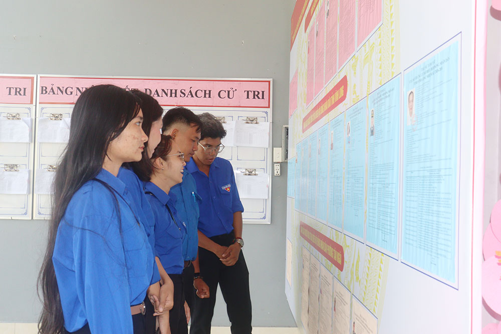 Cử tri trẻ theo dõi danh sách và tiểu sử tóm tắt của các ứng cử viên được niêm yết tại điểm bỏ phiếu.