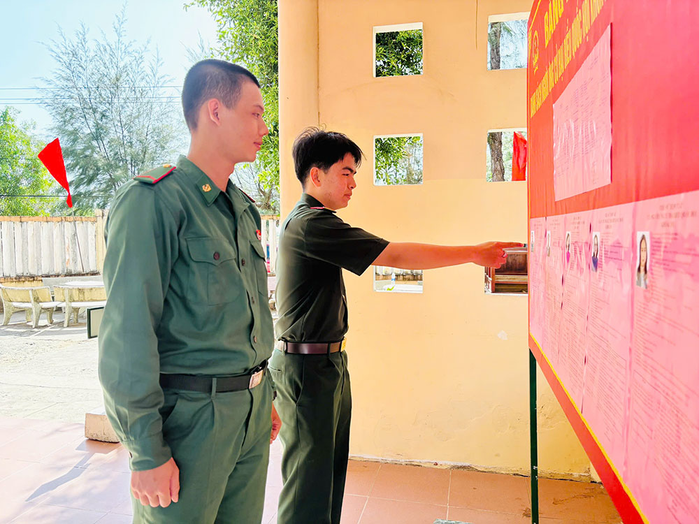 Chiến sĩ Nguyễn Trung Tuấn Kiệt (bìa trái) thuộc Tiểu đoàn Huấn luyện, Ban Chỉ huy Bộ đội Biên phòng tỉnh xem lại danh sách ứng viên trước khi bầu cử.