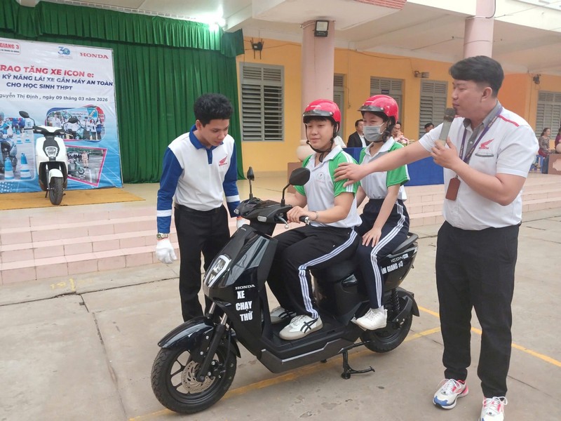  Học sinh được nhân viên hướng dẫn lái xe an toàn hướng dẫn kỹ năng sử dụng xe máy điện tại buổi tuyên truyền.
