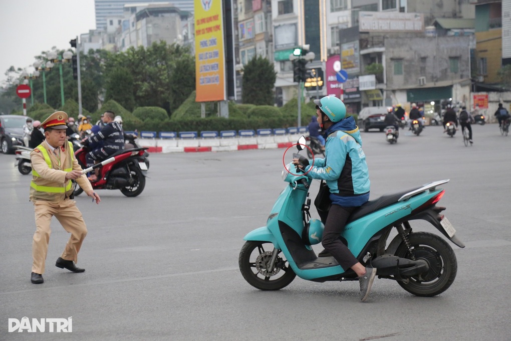 Cảnh sát giao thông yêu cầu dừng xe một tài xế xe ôm công nghệ vi phạm sử dụng điện thoại khi đang điều khiển xe máy (Ảnh: Trần Thanh).