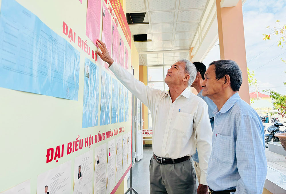 Cử tri xã Bình Đại tranh thủ xem lại thông tin các ứng cử viên trước thềm ngày bầu cử diễn ra.