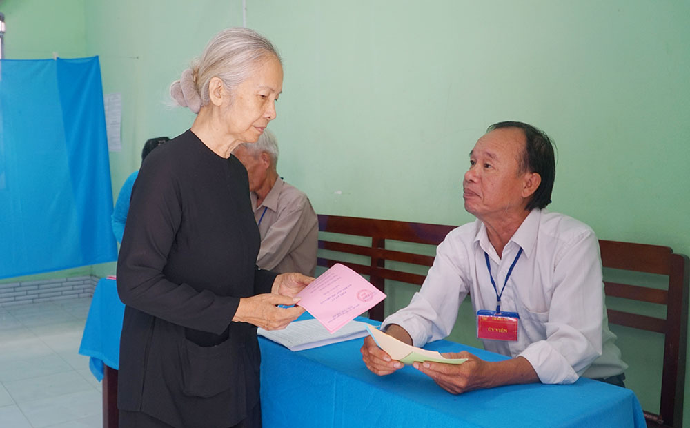 Tại khu vực bỏ phiếu 22, ấp Tân Lộc (xã Tân Lược), cử tri tín đồ Phật giáo Hòa Hảo được hướng dẫn quy trình bỏ phiếu. Ảnh: THẢO TIÊN