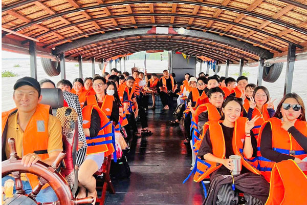 Du khách vui tươi, hào hứng trên tàu du lịch, trải nghiệm vẻ đẹp sông nước miệt vườn Vĩnh Long.


