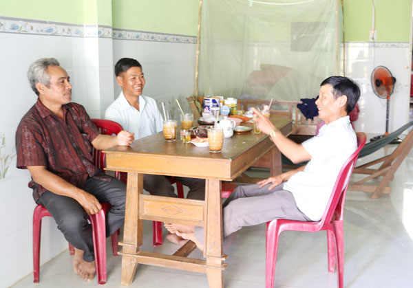 Ông Huỳnh Ngọc Thành trao đổi với cán bộ mặt trận địa phương về niềm vui trong căn nhà mới.

