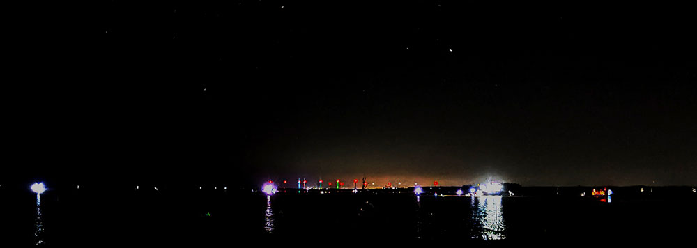 Sân nghêu Thới Thuận về đêm, cùng với ánh đèn pin soi bắt nghêu là những ngọn đèn đỏ các trụ điện gió ngoài khơi, sáng rực cả một vùng biển đêm.