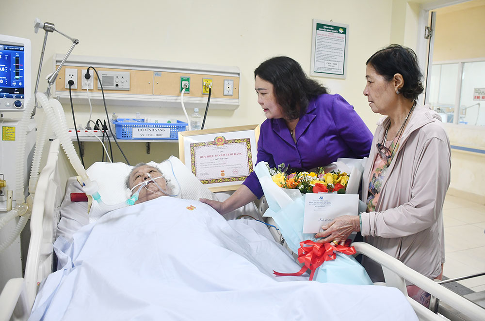 Đồng chí Hồ Thị Hoàng Yến trao Huy hiệu 55 năm tuổi Đảng cho đồng chí Hồ Vĩnh Sang, đang điều trị tại Bệnh viện Nguyễn Đình Chiểu.