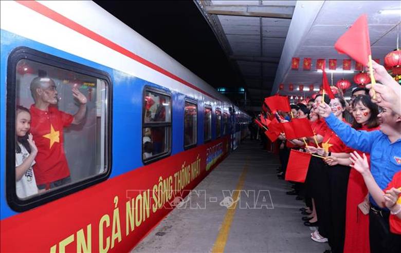 Lãnh đạo Tổng công ty Đường sắt Việt Nam vẫy cờ kèm những lời chúc may mắn đến những hành khách trên tàu SE1, tối 29/4 khi tàu lăn bánh rời Ga Hà Nội. Ảnh: Quốc Khánh/TTXVN

