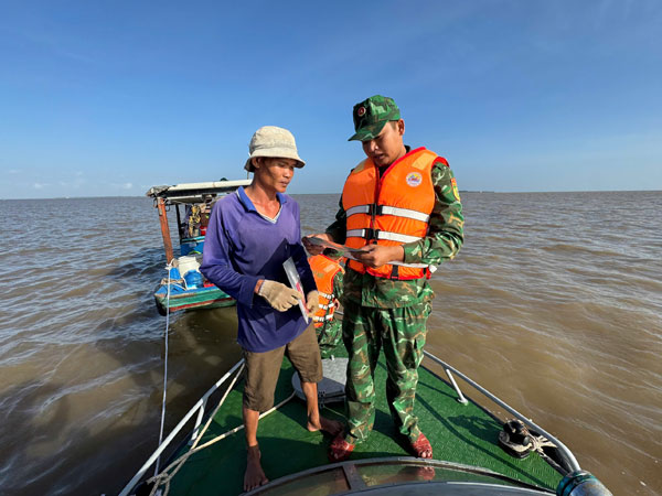 Cán bộ Đồn Biên phòng cửa khẩu Cảng Giao Long tuyên truyền pháp luật cho ngư dân.


