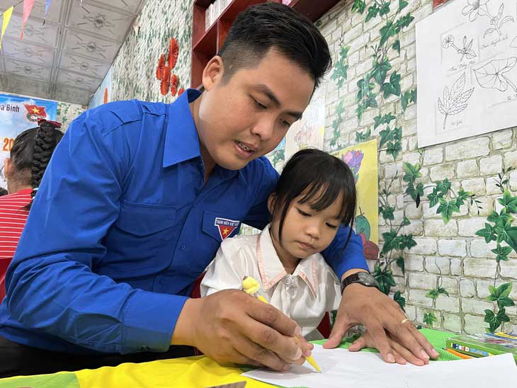 Thầy Khánh hướng dẫn từng nét vẽ cho các bé trong tiết học mỹ thuật của lớp học hè miễn phí - Ảnh: LAN NGỌC