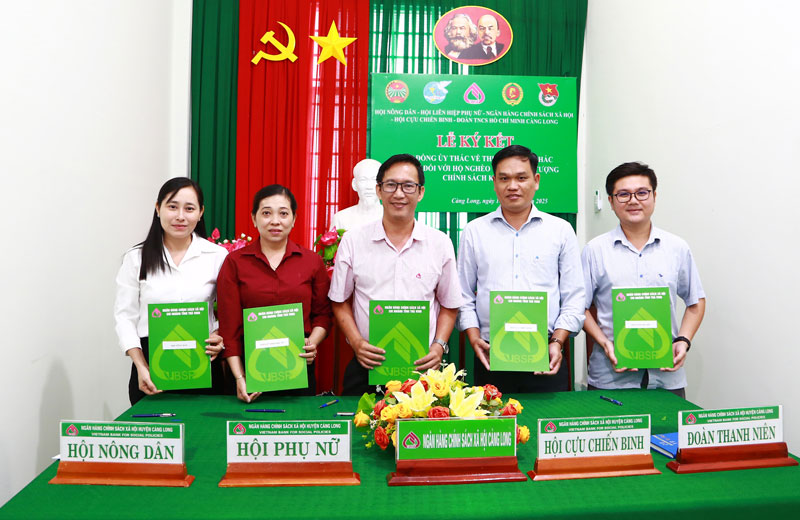 Ông Trần Quốc Phong- Giám đốc Phòng giao dịch NHCSXH Càng Long  (giữa) cùng lãnh đạo các tổ chức chính trị - xã hội xã Càng Long ký kết hợp đồng ủy thác.