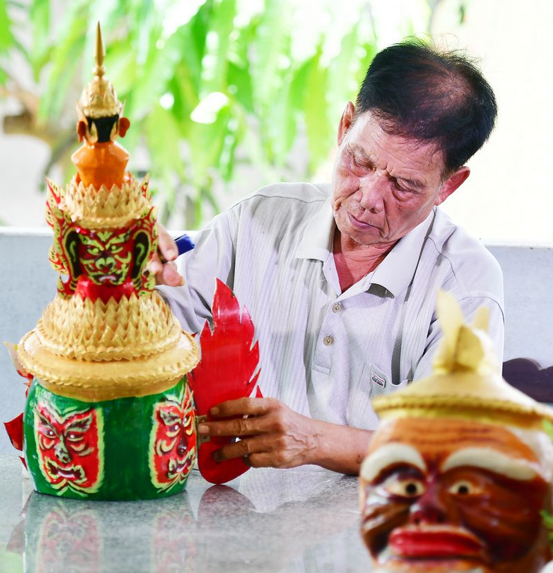 NNƯT Lâm Phên đang chế tác chiếc mão dùng trong biểu diễn Riềm-kê loại hình nghệ thuật biểu diễn truyền thống của người Khmer.

