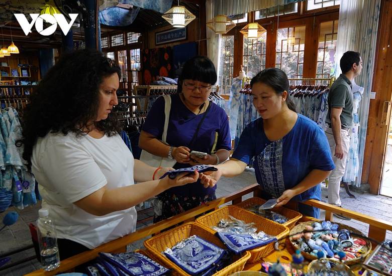 
Bà Lục Dũng Muội (đầu tiên bên phải) giới thiệu sản phẩm truyền thống địa phương cho du khách. Động trại Triệu Hưng khuyến khích phát triển các sản phẩm văn hóa sáng tạo dựa trên ngành nghề thủ công truyền thống