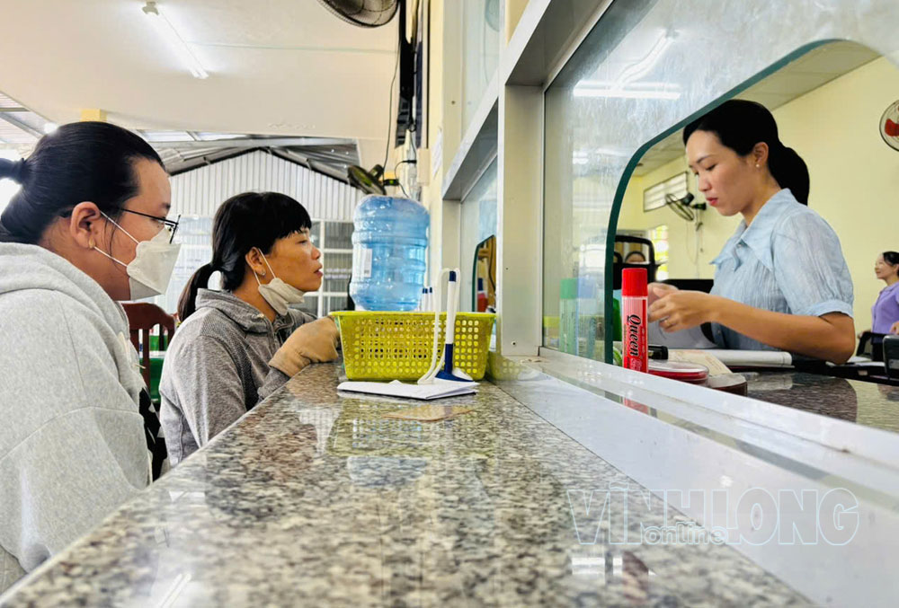 Cán bộ hướng dẫn người dân thao tác tra cứu thông tin thực hiện dịch vụ công. Ảnh: PHAN HÂN
