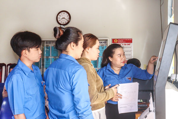 Đội hình thanh niên tình nguyện hỗ trợ người dân xã Trung Hiệp thực hiện thủ tục hành chính. Ảnh: CẨM HUỆ

