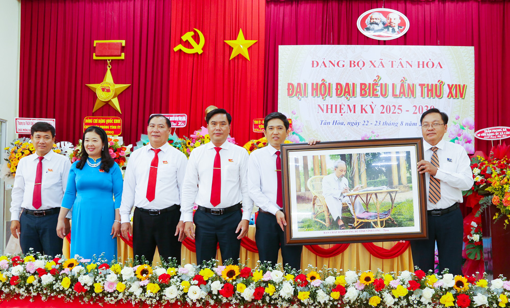 Đồng chí Tăng Chí Huấn- Tỉnh ủy viên, Phó Tổng Biên tập Báo và phát thanh, truyền hình Vĩnh Long tặng bức chân dung Chủ tịch Hồ Chí Minh chúc mừng đại hội. Ảnh: Ngọc Xoàn