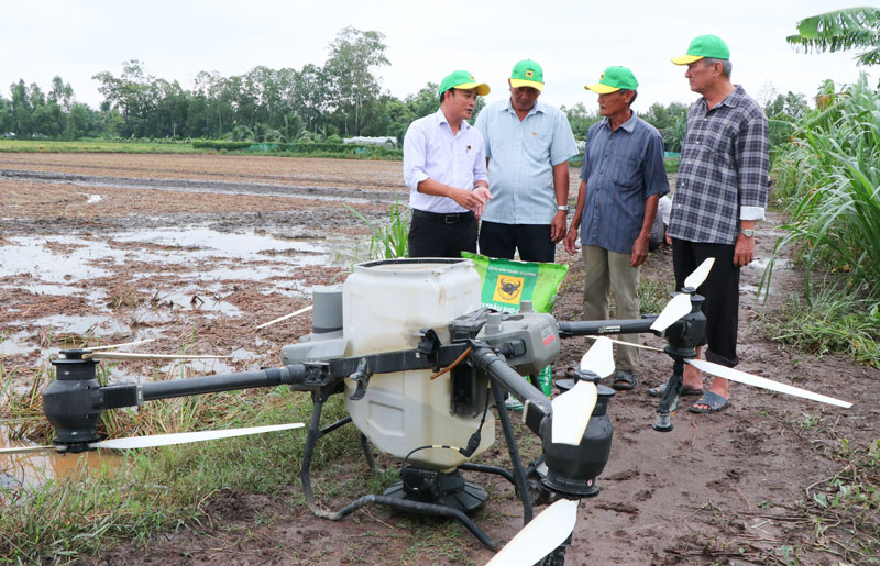 Cán bộ kỹ thuật hướng dẫn nông dân sử dụng phân bón kết hợp thiết bị bay trong mô hình lúa giảm phát thải tại HTX Nông nghiệp Phước Hảo.

