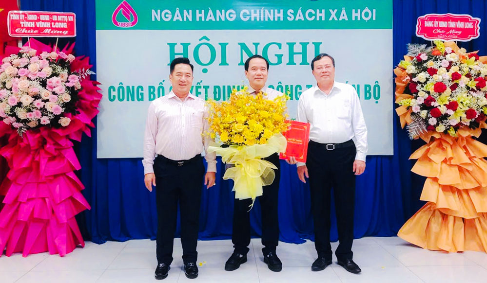 Ông Lê Văn Hẳn- Phó Bí thư Tỉnh uỷ, Chủ tịch Ủy ban MTTQ Việt Nam tỉnh Vĩnh Long (bìa phải), ông Huỳnh Văn Thuận - Phó Tổng Giám đốc NHCSXH (bìa trái) tặng hoa chúc mừng Giám đốc chi nhánh NHCSXH tỉnh Vĩnh Long- Lê Hoàng Phi.