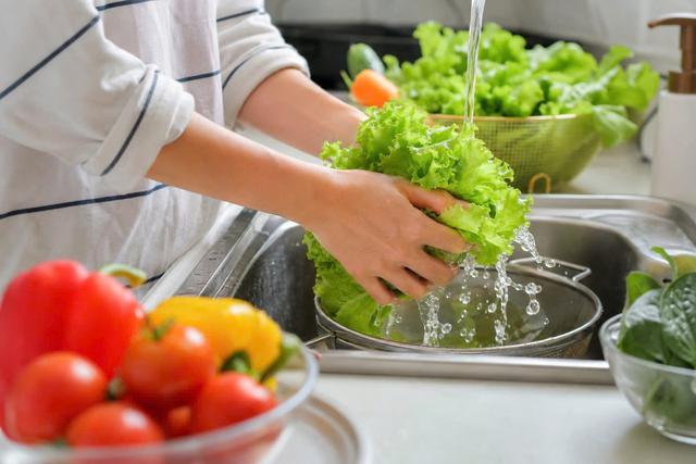 Đặt rau củ quả dưới vòi nước lạnh đang chảy hoặc cho vào rổ rồi xả nước. Với các loại có vỏ cứng, nên dùng bàn chải chuyên dụng chà nhẹ bề mặt.
Ảnh: N.Vy tạo từ AI