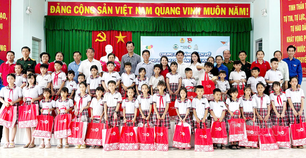 Đại biểu và các em học sinh nhận học phẩm chụp ảnh lưu niệm.