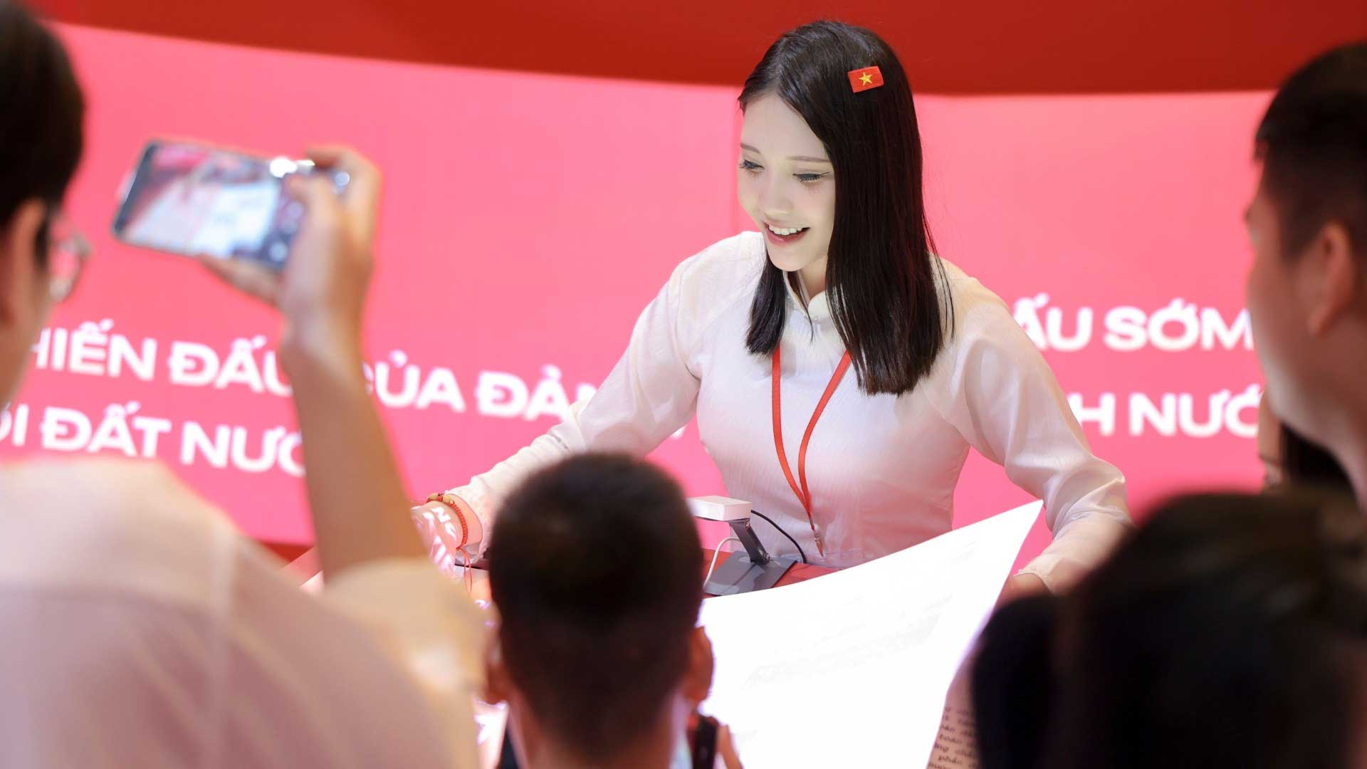 Đoàn Thùy Linh hướng dẫn khách tham quan tìm hiểu, trải nghiệm sách tương tác có tích hợp các công nghệ thông minh về các kỳ Đại hội Đảng. (Ảnh: XUÂN CHIẾN)