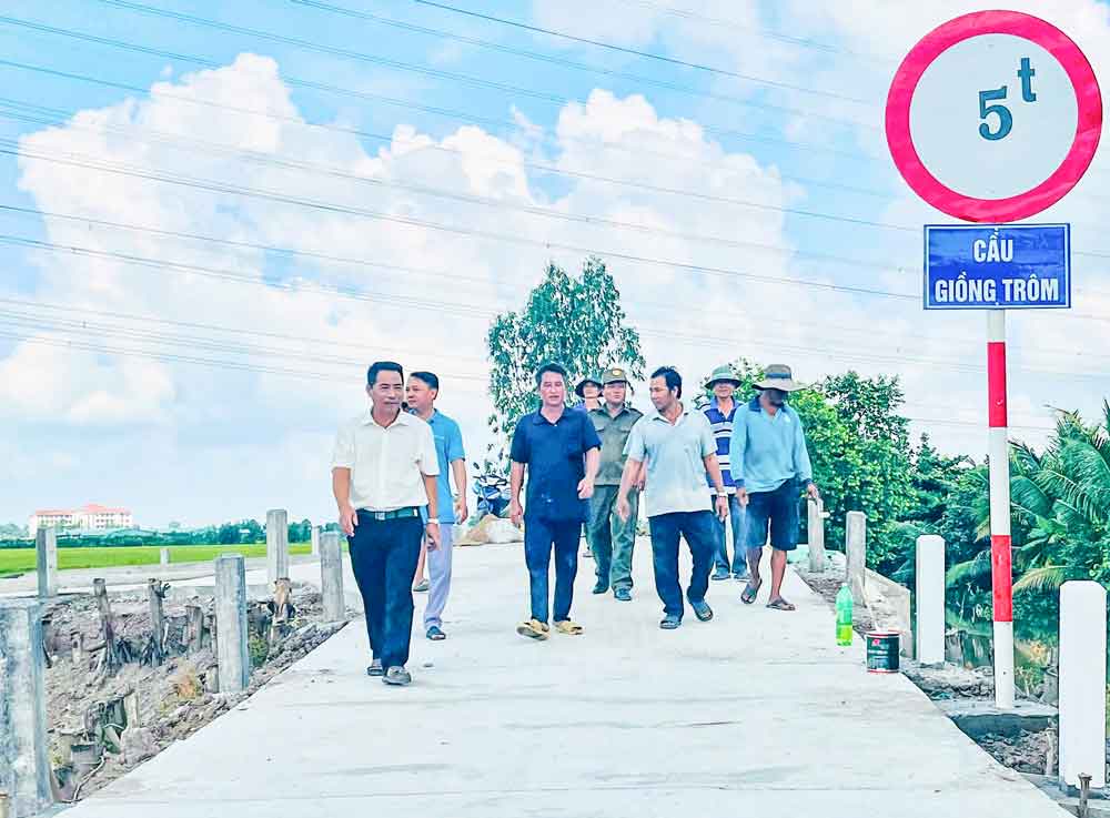 Ông Trần Văn Từ (đi trước) cùng người dân phấn khởi khi cầu nông thôn hoàn thành, đáp ứng nhu cầu đi lại hàng ngày.